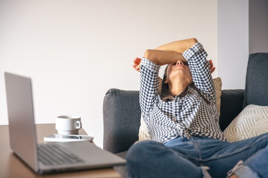 Tired from work young woman in front of a laptop.